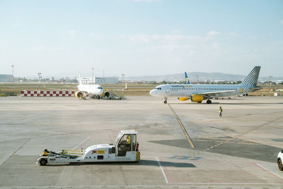 Vueling Airlines plane taxiing on an airport runway with clear sky.