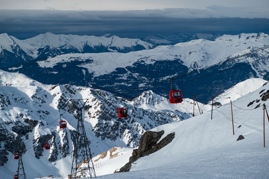 Red cable cars traverse the snowy peaks of the French Alps, offering a stunning winter landscape.