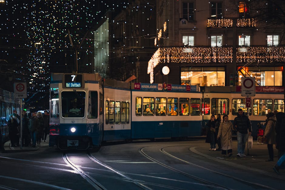 City street with a tram at night, festive lights and people walking in winter.