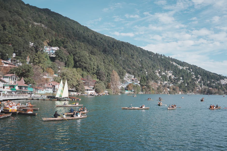 People enjoying boating on a picturesque lake surrounded by lush green mountains.