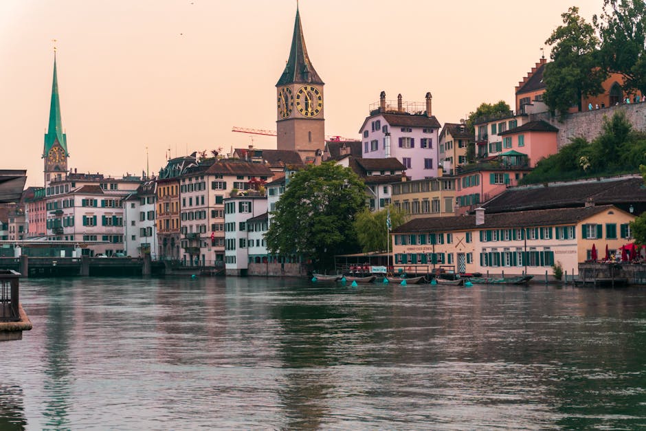 Explore the charming Limmat Riverfront in Zürich with its colorful historic buildings and iconic clock tower at sunset.