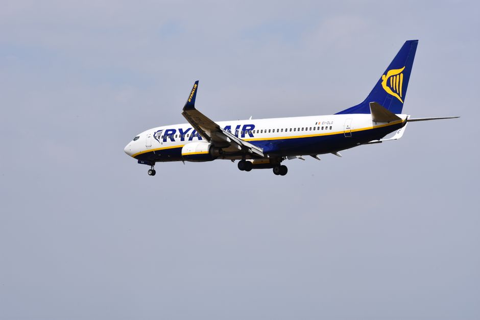 Ryanair airplane flying in clear blue sky, showcasing aviation and travel.