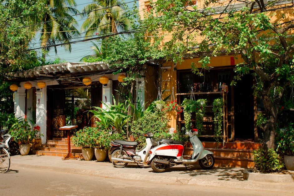 Vibrant street scene with lush greenery, motor scooters, and tropical architecture.