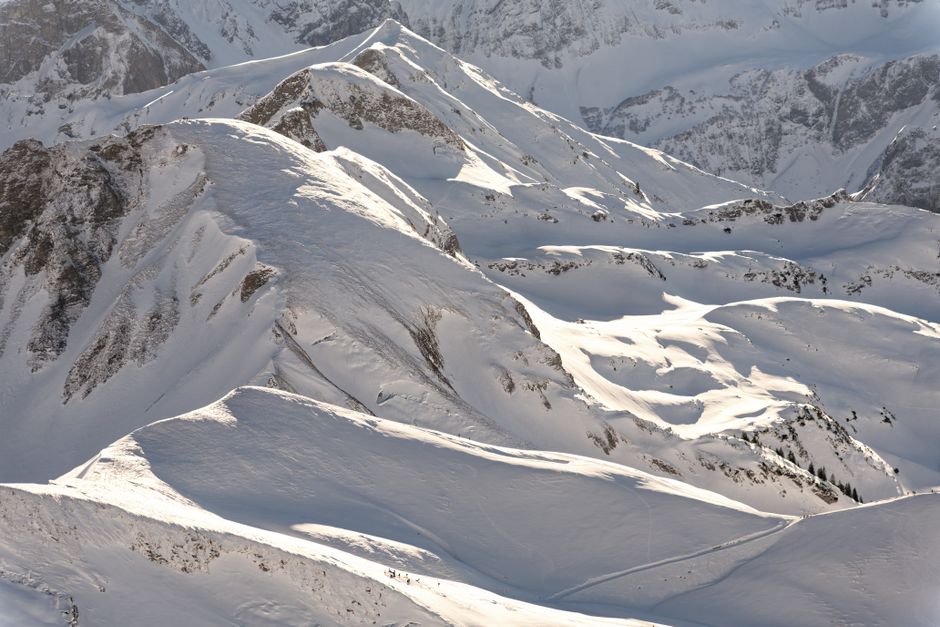 A stunning winter landscape showcasing snow-covered mountains under the bright sunlight.