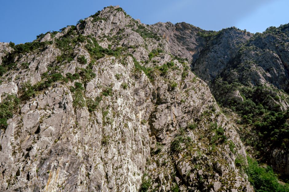 Explore the stunning rocky cliffs of Koman, Shkodër County, Albania, under a clear blue sky.