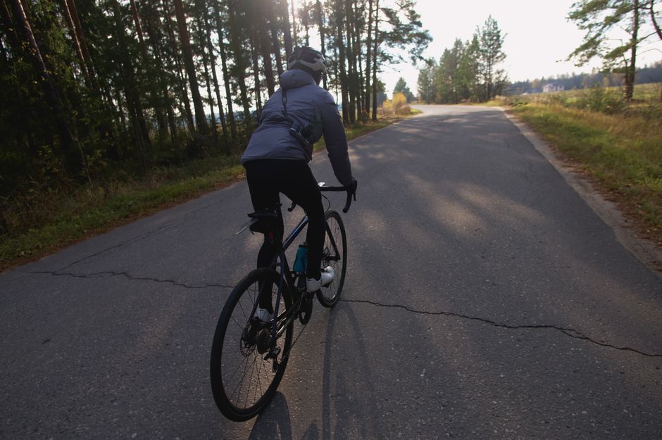 Cyclist riding a bike on a forest road during daylight, capturing freedom and adventure.