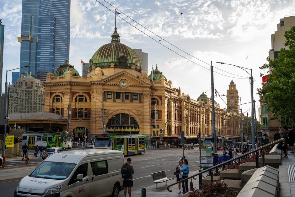 Vibrant view of Flinders Street Station in Melbourne with trams and city traffic.