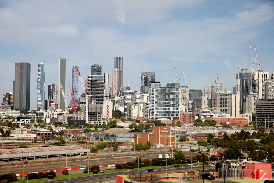 View of Melbourne's skyline featuring tall skyscrapers and construction cranes under a clear sky.
