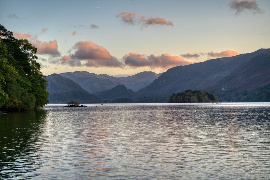 Tranquil lake with mountains in the background at sunrise, capturing nature's beauty.