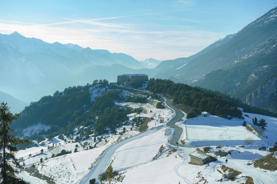 Beautiful aerial landscape showcasing snow-covered mountains and a rural valley during winter.