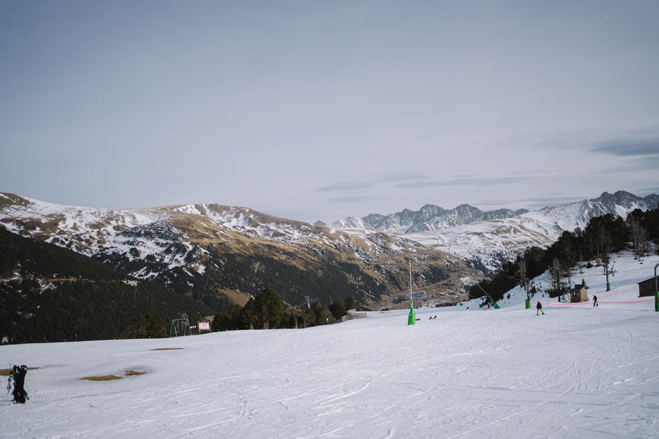 Snowy alpine landscape featuring skiers and a ski resort in winter.