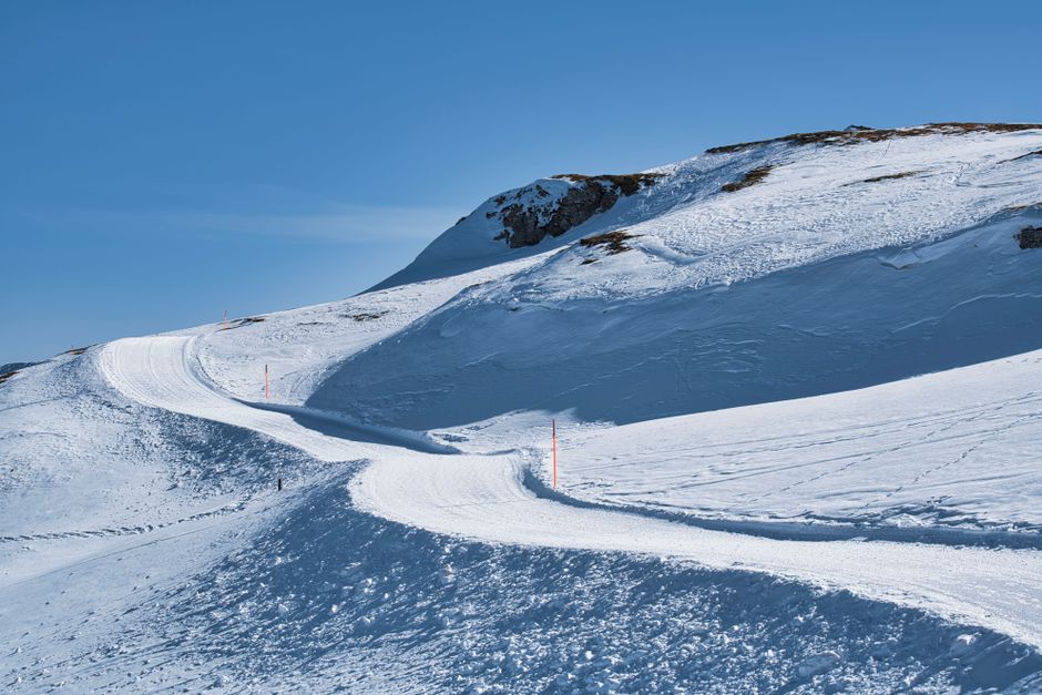 Scenic snowy mountainside with winding road and blue sky in the winter season.