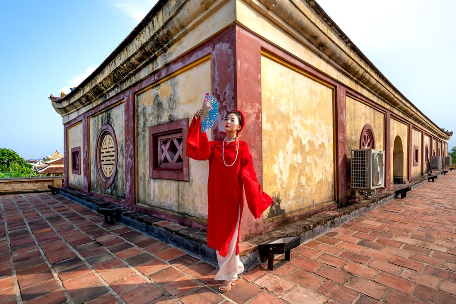 Young Vietnamese woman in red Ao Dai at historic temple