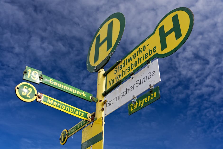 Low angle view of a city bus stop signpost against a vivid blue sky.