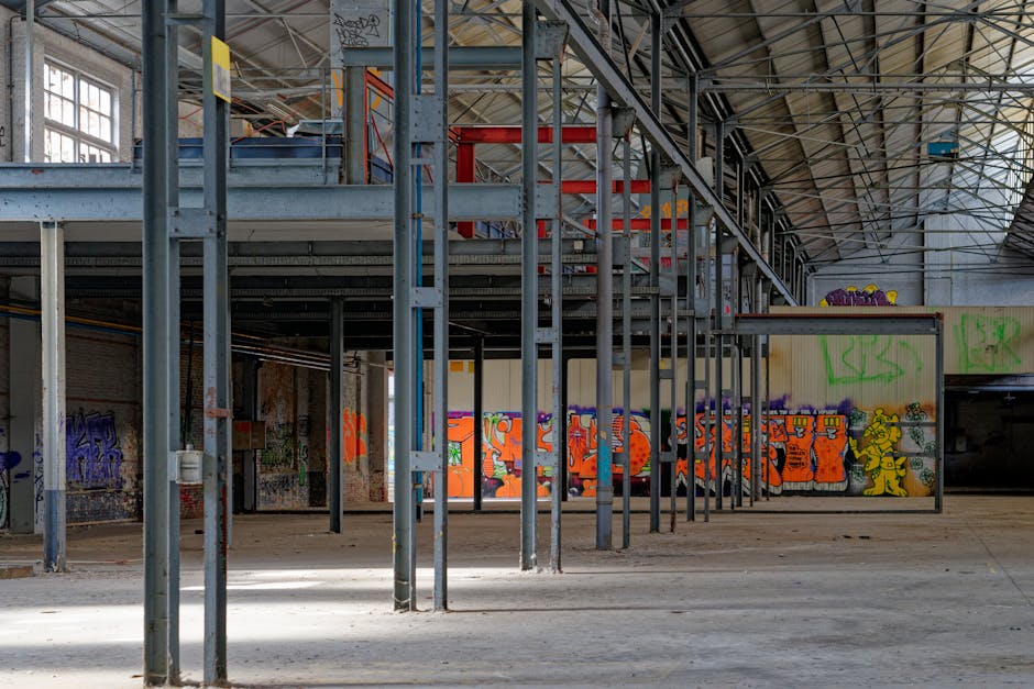 Graffiti-covered interiors of an abandoned warehouse showcasing urban art and industrial architecture.